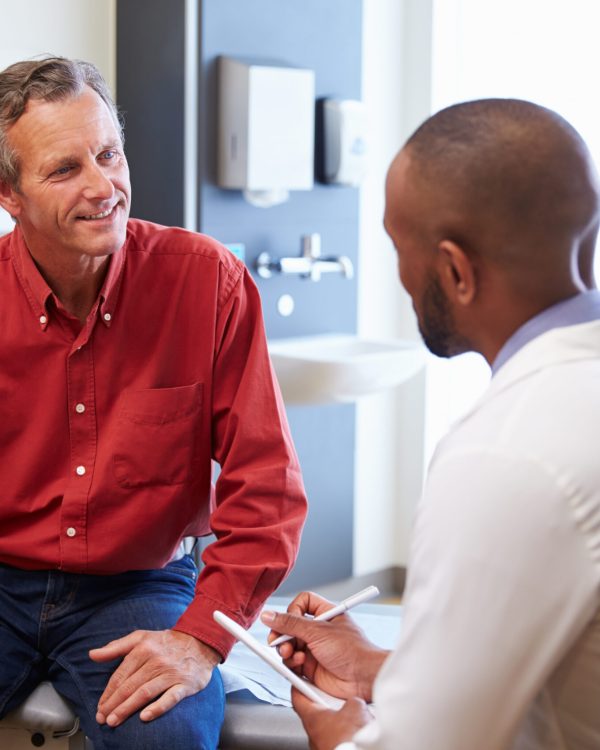 Male Patient And Doctor Have Consultation In Hospital Room